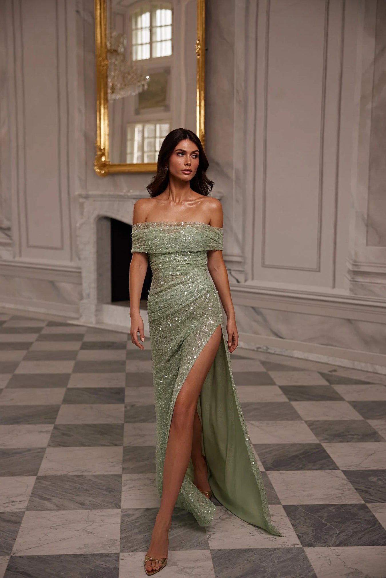 woman in sage sequin dress in a lavish dance hall surrounded by marble flooring